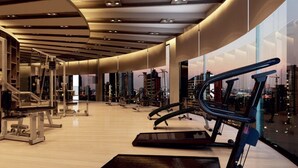 Ein modernes Fitnessstudio mit Cardiogeräten, Kraftmaschinen und einem großen Fenster mit Blick auf die Stadt.