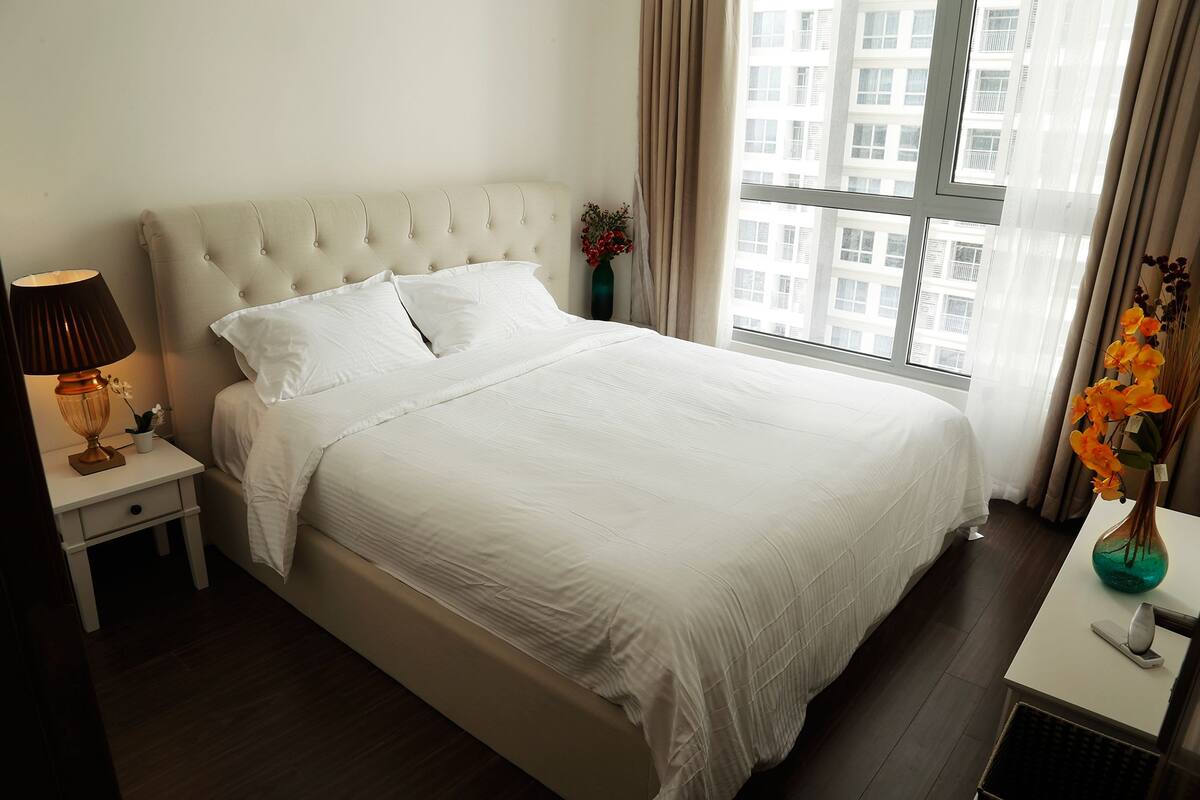 Een opgemaakt bed met witte lakens in een hotelkamer.