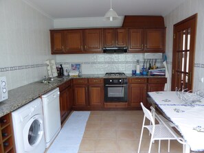 Enjoy meals and snacks in the compact kitchen with an oven, washing machine, and dining area.