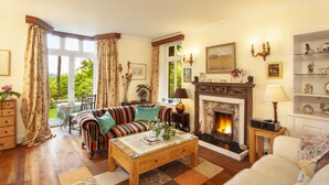 A living room with a fireplace, a sofa, a striped armchair, and a coffee table. - Chapel Knap, Porlock Weir (Porlock Weir)