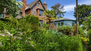A large stone house with a green roof, surrounded by lush greenery and a conservatory. - Chapel Knap, Porlock Weir (Porlock Weir)