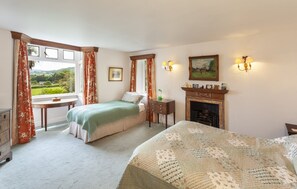 A bedroom with a bed, a desk, a fireplace, and a view of the outdoors. - Chapel Knap, Porlock Weir (Porlock Weir)