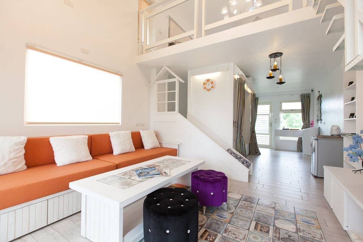 Ein geräumiger Wohnbereich mit Sofa, Couchtisch und einer Treppe zu einer oberen Ebene.