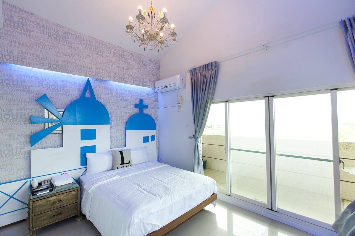 Ein Schlafzimmer mit einem großen Bett, einer Kandelaberleuchte, Meerblick und einem Balkon.
