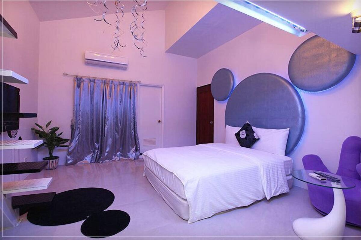 Ein modernes Schlafzimmer mit Bett, Schreibtisch, Stuhl und einer Topfpflanze.