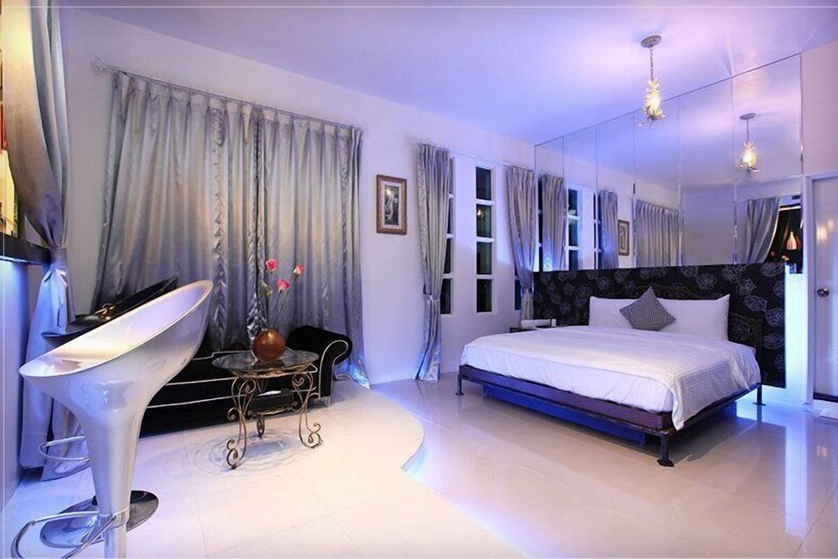 Ein modernes Schlafzimmer mit einem großen Bett, einem Frisiertisch mit Spiegel und einem einzigartigen weißen Sessel.