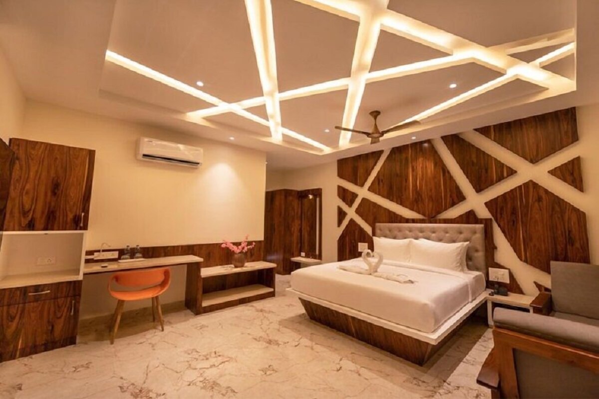 A modern bedroom with a bed, desk, and seating area.
