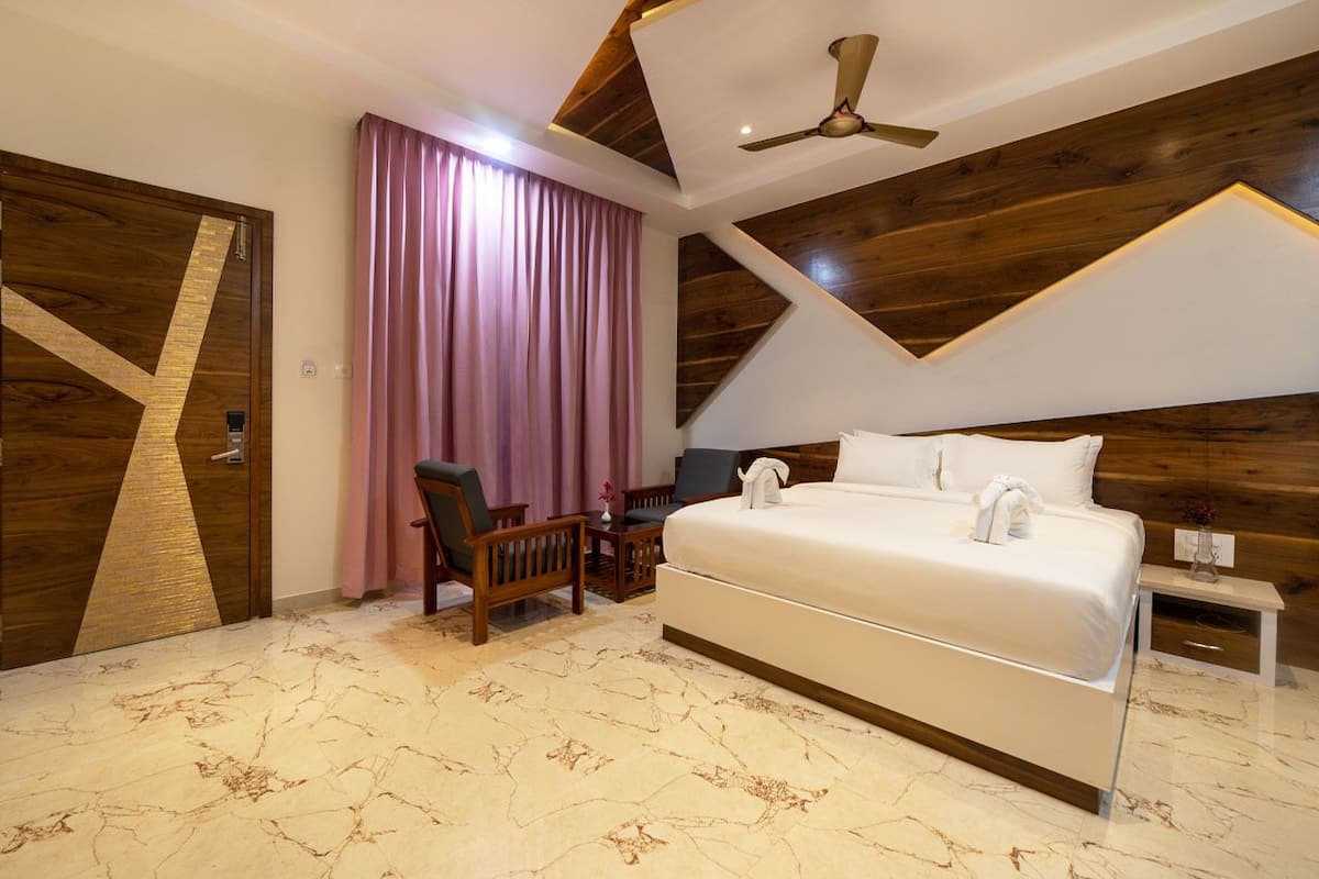 A modern bedroom with a large bed, wooden ceiling, and a desk with chairs.