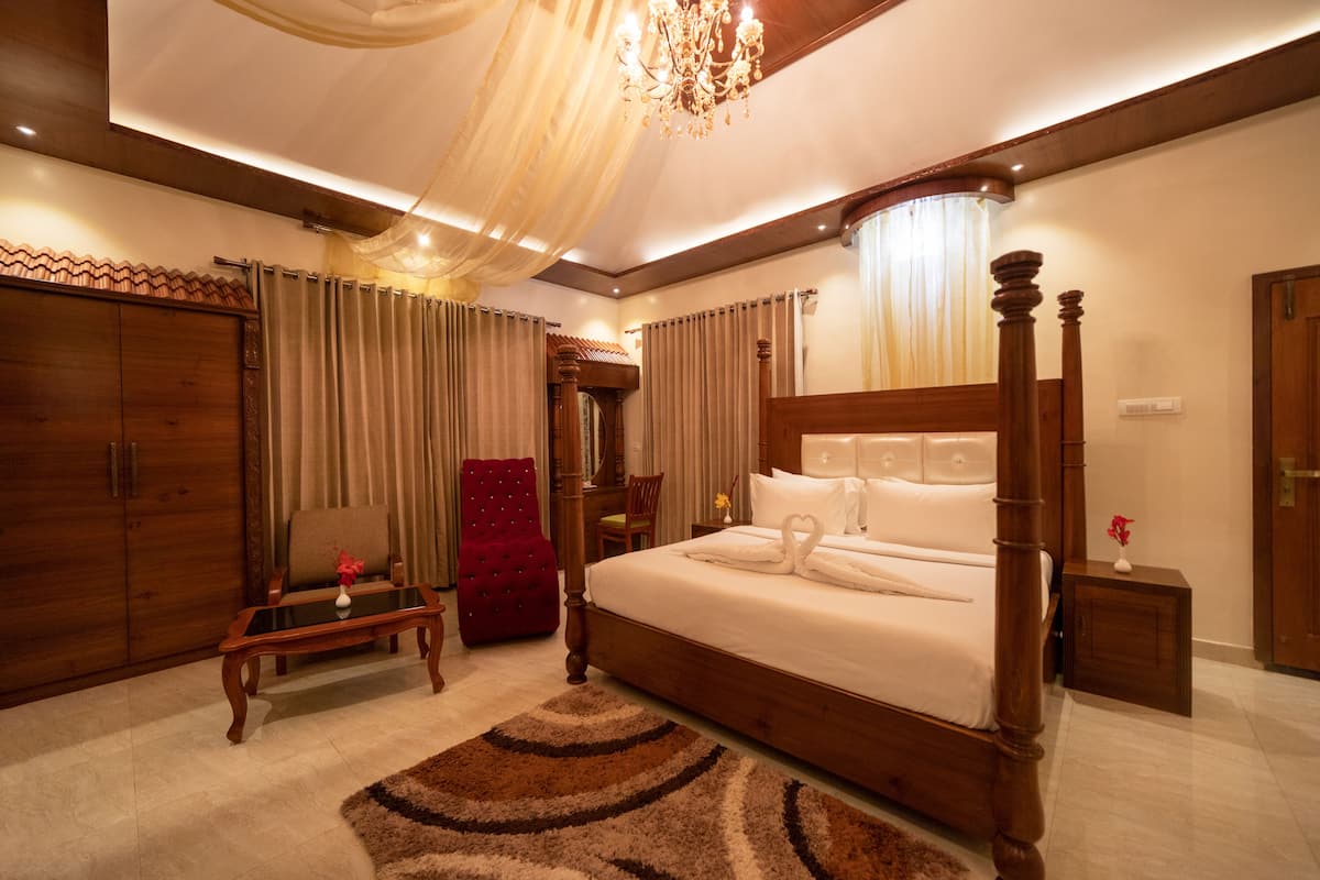 A spacious bedroom with a large bed, wooden wardrobe, and a red armchair.