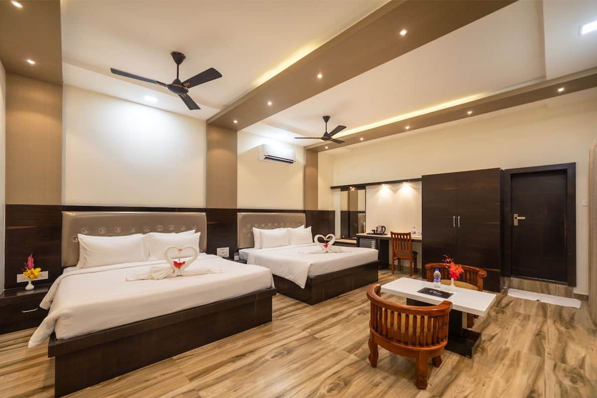 A hotel room with two beds, a desk, chairs, and a wardrobe.