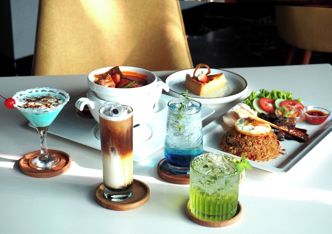 Une table dressée avec divers plats et boissons, notamment un dessert, un bol de soupe et une assiette de salade.