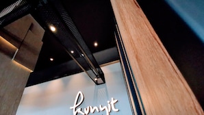 Interior de restaurante con diseño moderno, destacando un cartel en la pared que dice 'kunjit restaurant'.