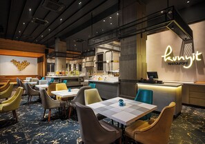 Interior de restaurant amb taules i cadires, una barra i un rètol de neó.