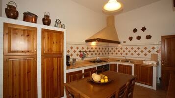 A kitchen with wooden cabinets, a central island with a fruit bowl, and a hanging light fixture.