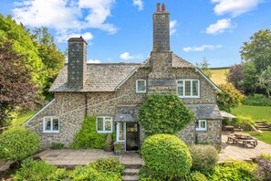 A stone house with a chimney, a front door, and a patio with outdoor furniture.