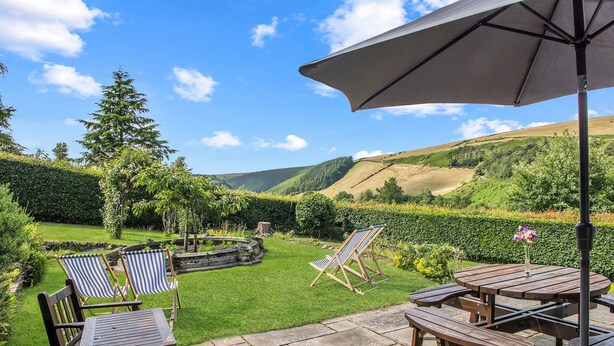 Une terrasse avec des meubles en bois, une table et un parasol.