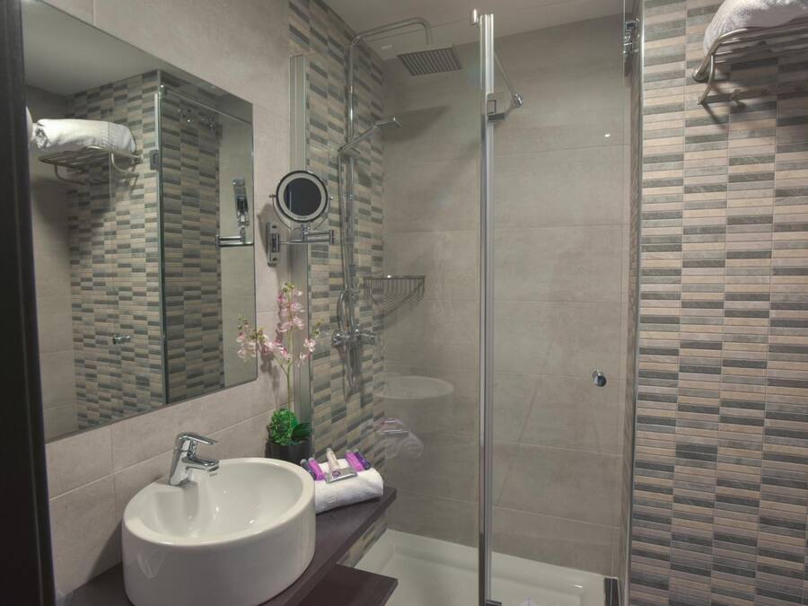 Un baño moderno con cabina de ducha de vidrio, un espejo grande y un lavabo blanco.
