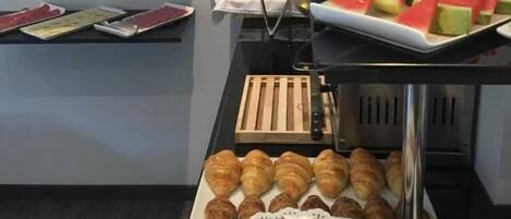 Un buffet proposant une variété de plats, notamment des pastèques, des raisins et des pâtisseries.