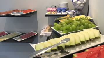 A buffet with various food items including watermelon slices, grapes, and cheese.