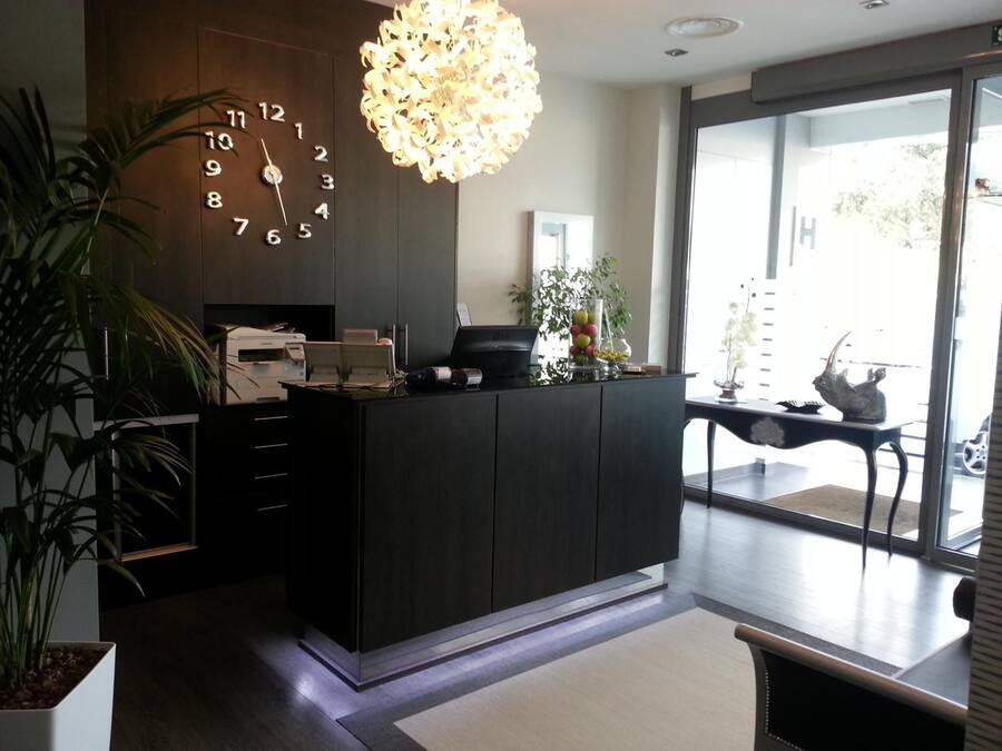 Un mostrador de recepción moderno con un reloj, una impresora y una planta decorativa.