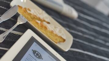 A tablet displaying hotel information, a spoon, and a partially eaten dessert on a table.