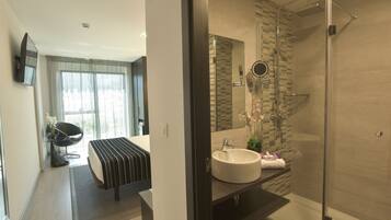 Un baño moderno con ducha envuelta en vidrio, un lavabo grande y un mueble de tocador.