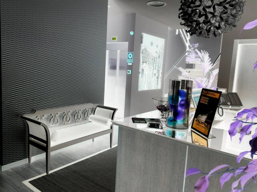 A modern reception area with a white sofa, a glass desk, and a decorative black chandelier.