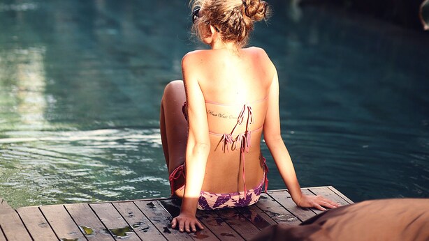 A person sitting by a pool with lush greenery in the background. - M Boutique Hostel (Keroboken Kelod)