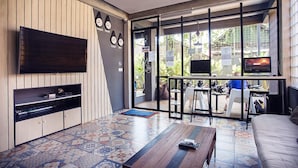 A modern living room with a flat-screen TV, a wooden coffee table, and a sofa. - M Boutique Hostel (Keroboken Kelod)