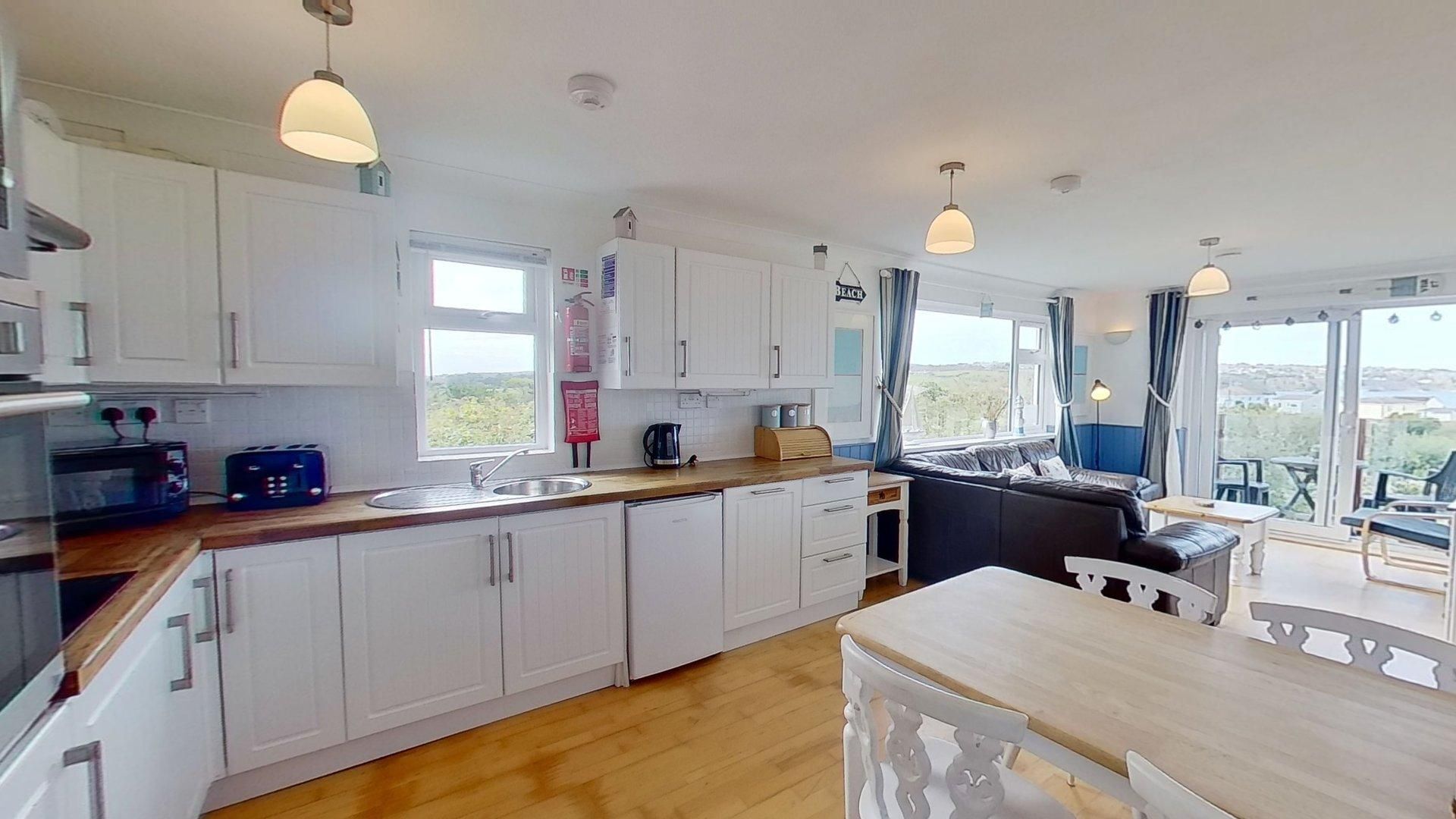 A modern kitchen with white cabinets, a wooden countertop, and a dining area with a table and chairs.