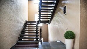 A modern staircase with a black railing and a potted plant beside it. - De'Mar Hotel (Bishkek)