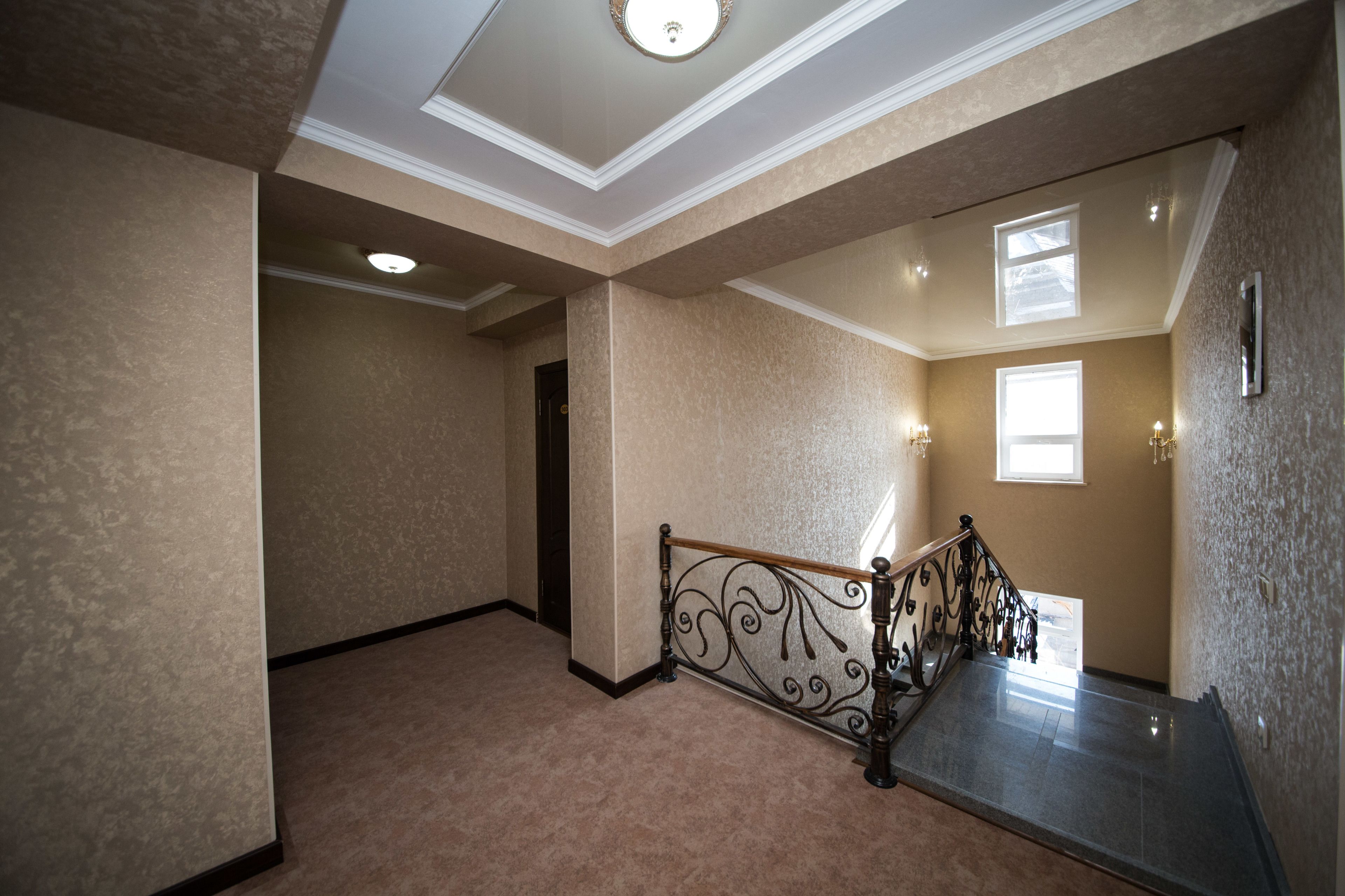 A spacious hallway with a marble staircase, a ceiling with recessed lighting, and a view of the outside through a window.