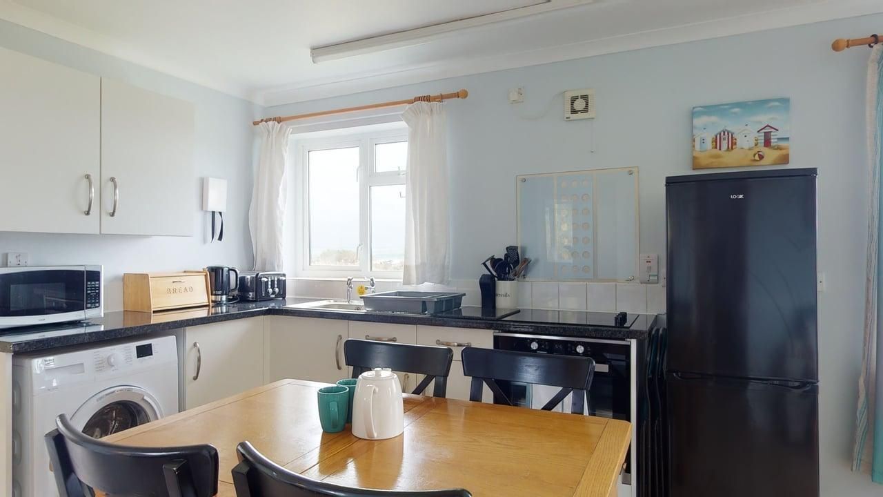 A compact kitchen with a washing machine, microwave, and a black refrigerator.