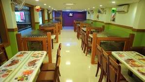 A restaurant with booths and tables, each with a menu. - Castle International Premium Hotel (Somvarpet)
