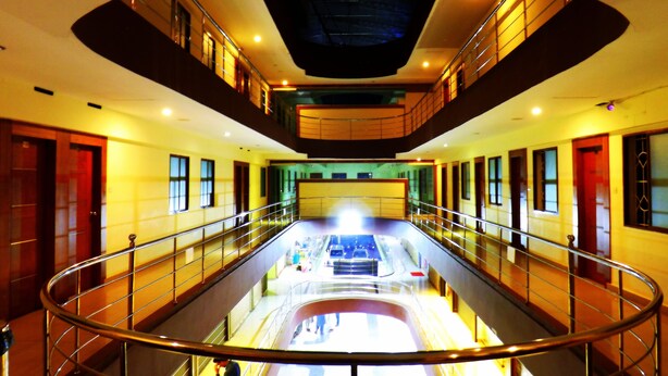 A multi-level interior with a central escalator, railings, and a high ceiling. - Castle International Premium Hotel (Somvarpet)