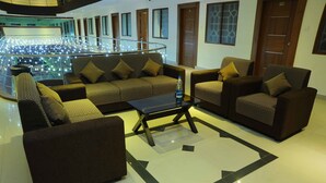 A spacious lobby with a central seating area, a glass railing, and a staircase leading to an upper level. - Castle International Premium Hotel (Somvarpet)