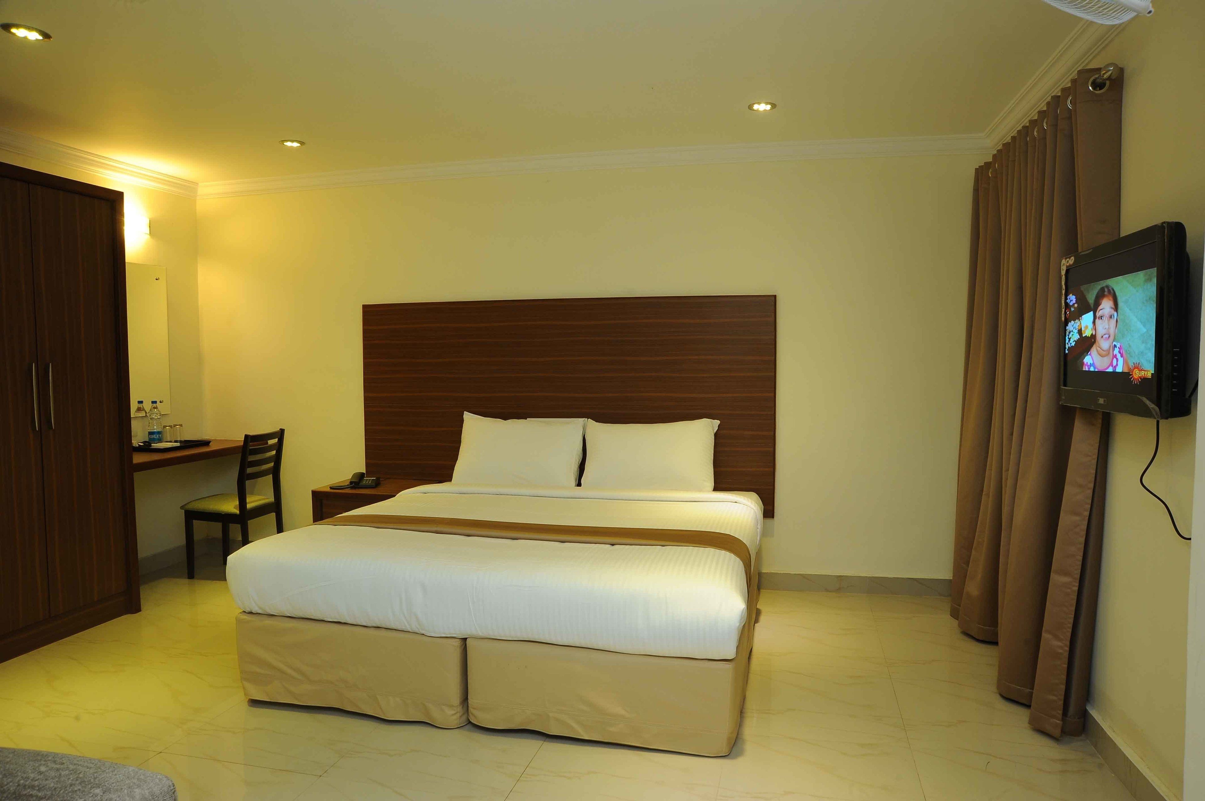 Een hotelkamer met een groot bed, een bureau, een stoel, een televisie en een kledingkast.