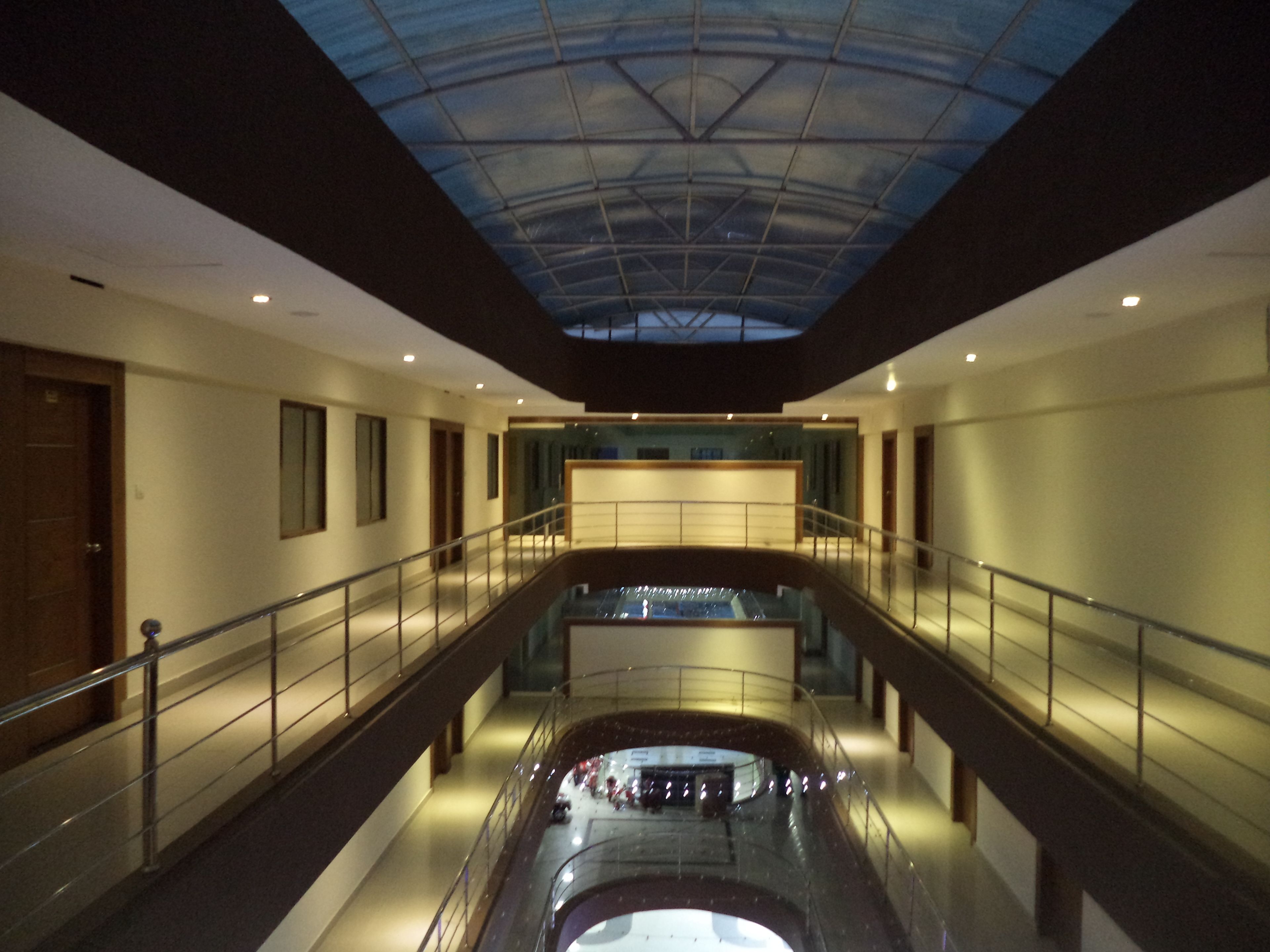 A multi-level interior with glass railings, a central atrium, and a skylight.