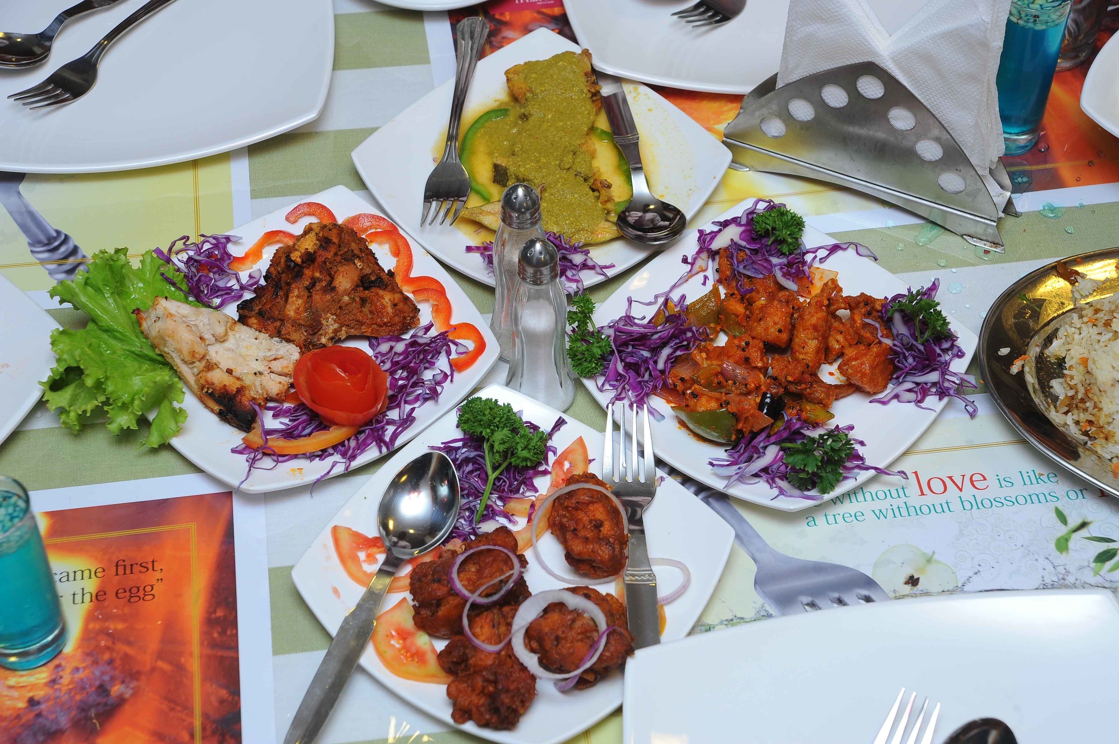 A table with various dishes, including grilled chicken, rice, and vegetables.