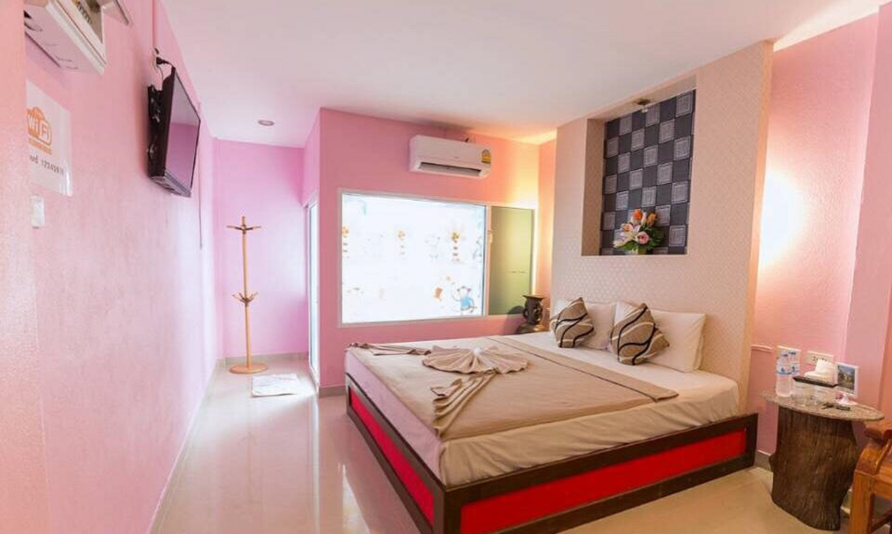 A bedroom with a bed, a bedside table, a mirror, and an air conditioning unit.