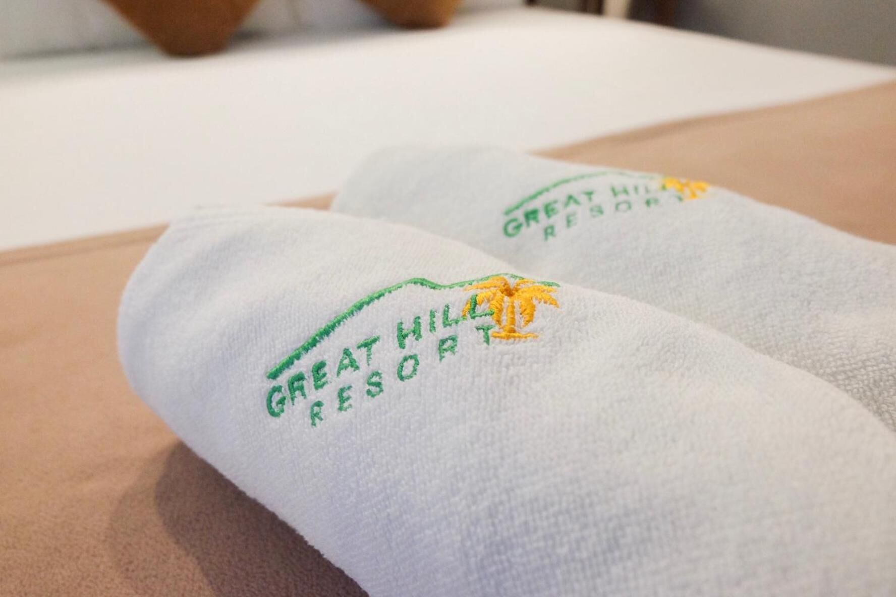 Zwei weiße Handtücher mit eingesticktem Text und einem Palmen-Logo, das auf ein Hotel oder Resort hinweist.