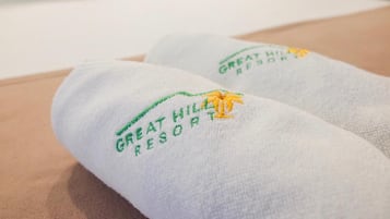 Zwei weiße Handtücher mit eingesticktem Text und einem Palmen-Logo, das auf ein Hotel oder Resort hinweist.
