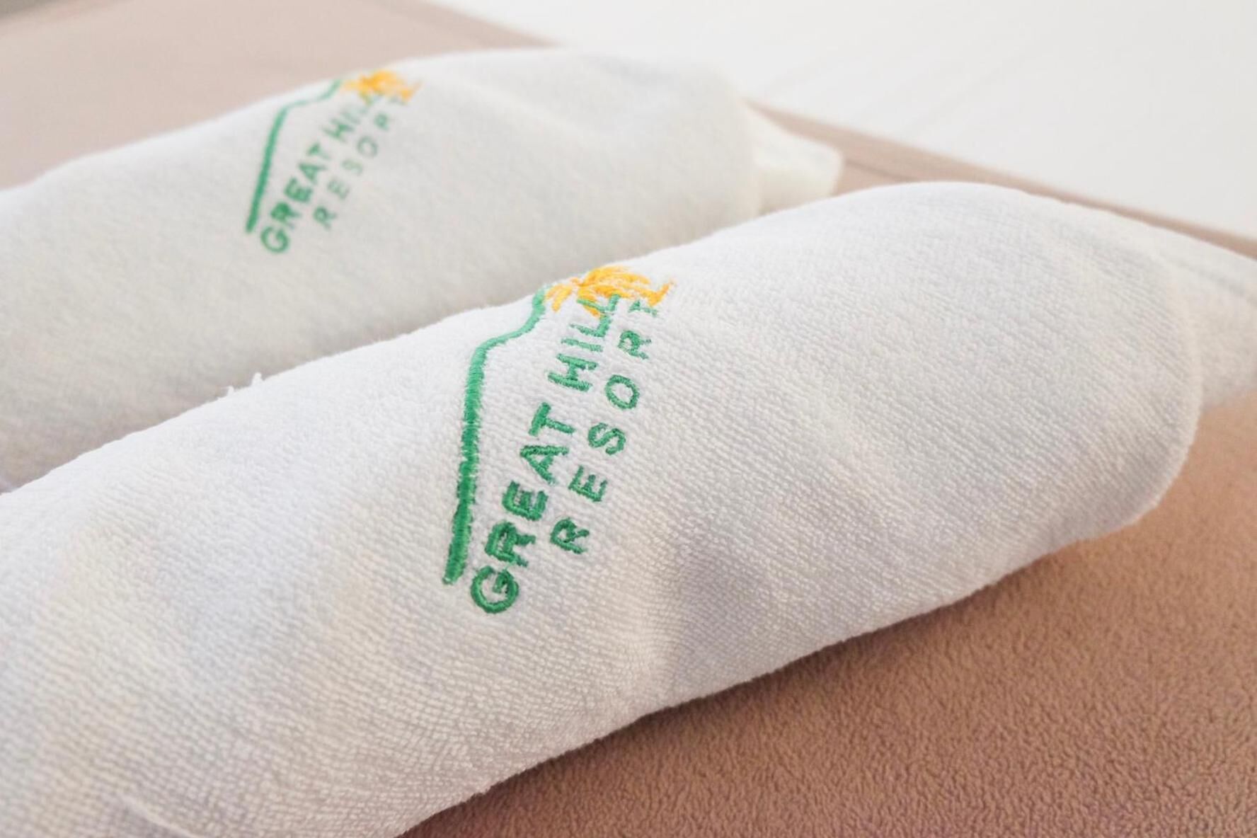 Two white towels with embroidered text reading "GREAT HILL RESORT".