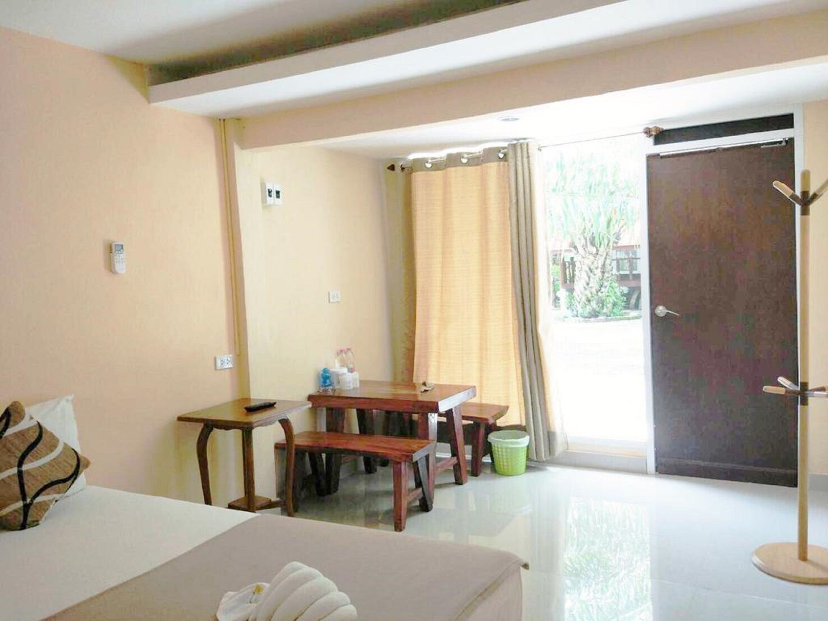 A hotel room with a bed, a desk, a chair, and a coat rack.