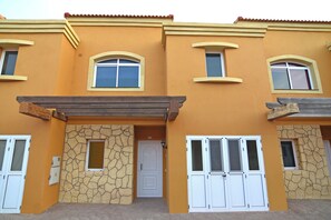Un edificio con fachada amarilla, puertas blancas y detalles de piedra.
