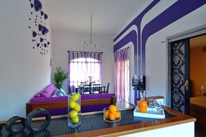 A modern living room with a sofa, dining table, and kitchen counter.
