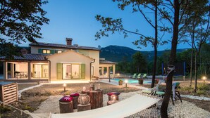 Una villa con piscina, mobiliario de exterior y una hamaca.