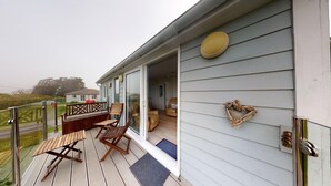 A covered deck with wooden furniture and a heart-shaped decoration on the wall.