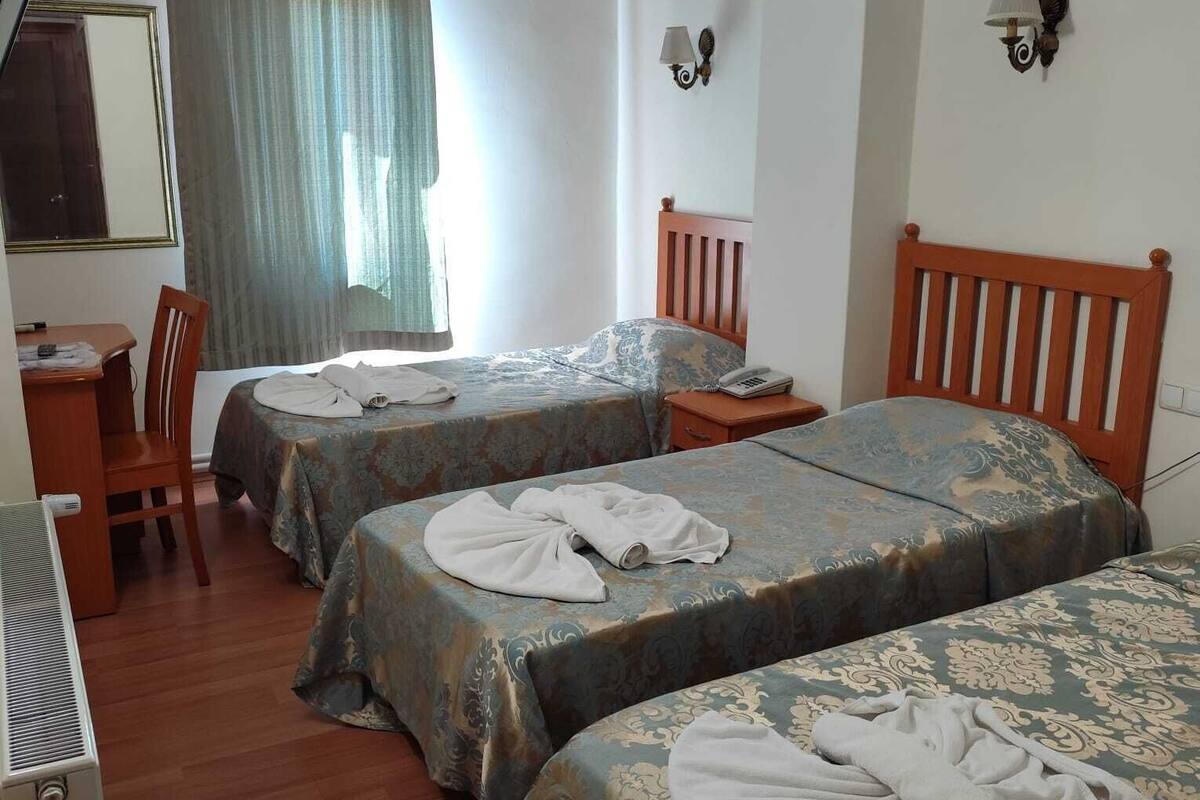 A hotel room with two beds, a desk, a chair, and a mirror.