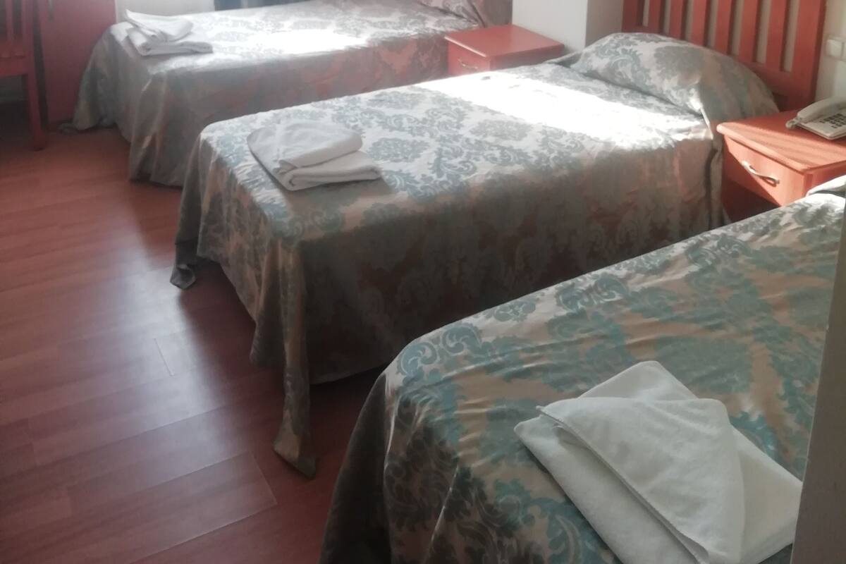 A hotel room with two single beds, a wooden desk, and a chair.
